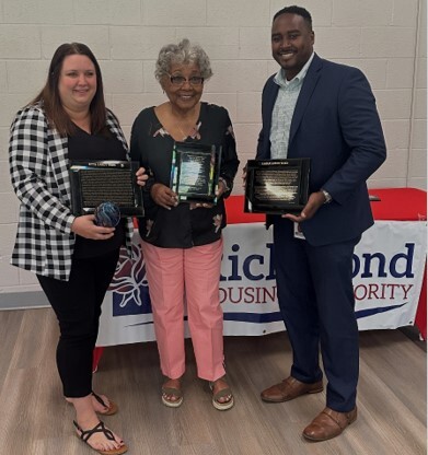 Ms. Etta with Roxie and Mr. Keon standing in front of a table holding plaques.