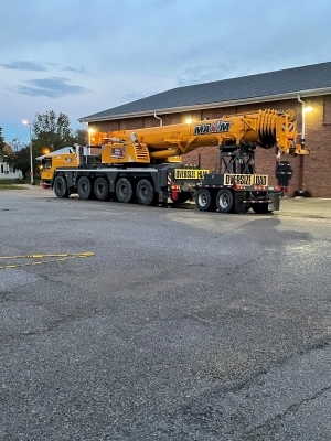 Large truck with oversize load banners carrying a crane.